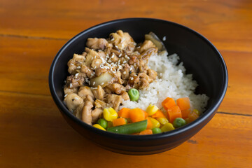 Teriyaki chicken rice bowl with vegetables and corn on wooden background
