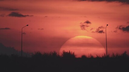 Daybreak in the morning is marked by the large sun rising gradually from above the horizon. In the winter morning, the sun rises amid a hazy or foggy sky. Dawn sunrise on the natural landscape.