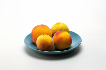 ripe peaches in a shallow dish, on a white milky background.