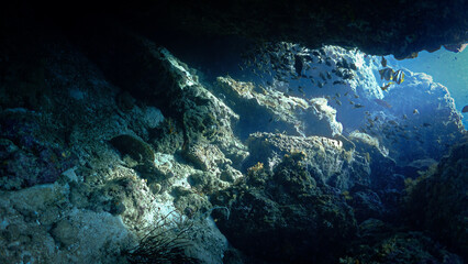 Underwater photo from a scuba dive inside a cave and tunnel with rays of light
