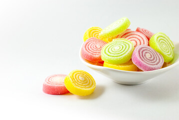 Marshmallows with gelatin dessert colorful in a white container on a white background with copy space on the left.