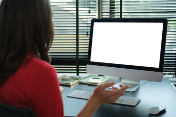 Young female office worker sitting front computer with blank empty screen for your information or content.