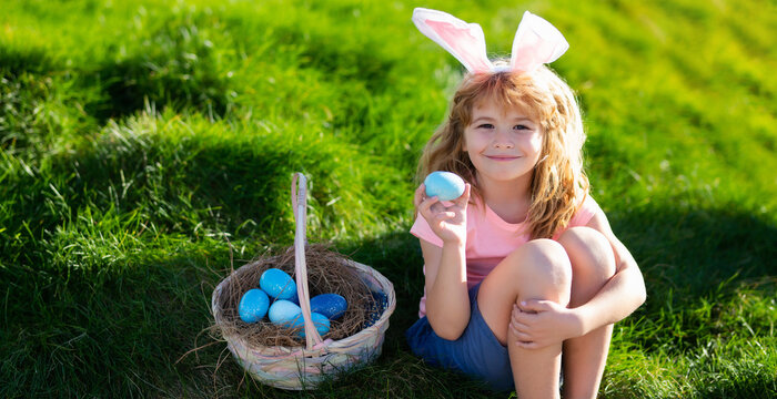 Horizontal photo banner for website header design. Happy Easter for children. Boy in bunny ears with colorful eggs play and hunting easter eggs outside. Cute child with easter basket on grass.