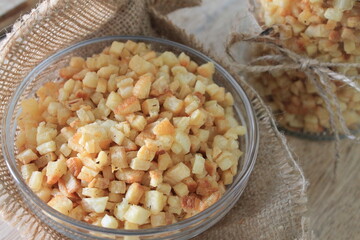 Indonesian snack in the form of small fried cassava slices called balok in a glass bowl lined with burlap and a glass jar on a wooden table

