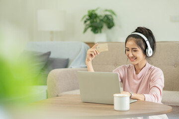 Fototapeta premium Asian woman sitting at home listening to music reading at home on holiday