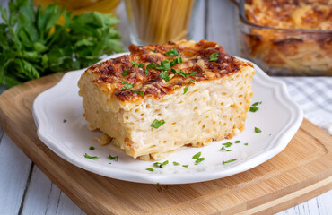 Pasta casserole bechamel sauce topped with melted mozzarella cheese and served in a white baking dish on a table (Turkish name; firinda makarna or firin makarna)