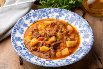 Turkish traditional tas kebab with potato, pea and tomato in a white plate - Kebap. Turkish name; Tas kebabi