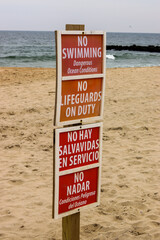 Sign on the beach as the waves crash along the jetty 