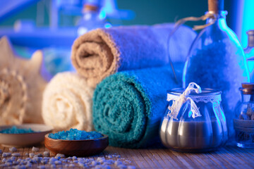 Obraz na płótnie Canvas Spa and wellness concept. Bottles with bath and spa cosmetics, rolled up towels, bath salts and care products on wooden rustic paneling.