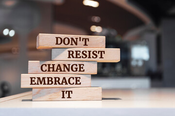 Wooden blocks with words 'Don't resist change embrace it'.