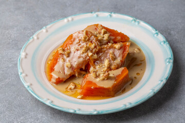 Pumpkin dessert with tahini and walnuts on a white porcelain plate