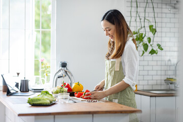Portrait of attractive asian japanese woman in kitchen at home, young girl browsing website on tutor cooking class and doing for kitchen, cutting vegetables, cooking, cooking concept.