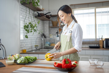 Portrait of attractive asian japanese woman in kitchen at home, young girl browsing website on tutor cooking class and doing for kitchen, cutting vegetables, cooking, cooking concept.