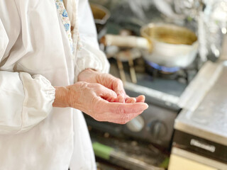 台所で手をさする高齢女性