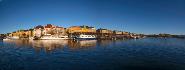 Fototapeta premium Moored boats at the pier Strandvägen in the bay Ladugårdsviken, a low winter solstice a sunny and snowy day in Stockholm