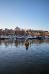 Old boat wood dolphins, moored boats at the pier in the island Skeppsholmen, a low winter solstice a sunny and snowy day in Stockholm