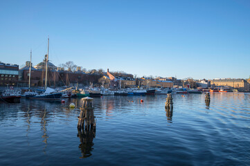 Fototapeta premium Old boat wood dolphins, moored boats at the pier in the island Skeppsholmen, a low winter solstice a sunny and snowy day in Stockholm