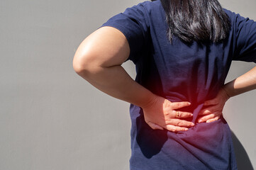 A woman uses her hand to press on the waist due to back pain and waist pain.