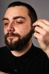 Obraz premium Beard care. Closeup of male face and pipette with a oil for a beard growth