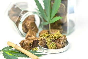 Dried marijuana in a jar with green marijuana leaves and rolls on a white background. Medical marijuana dispensary Alternative medicine Cannabis plantation for medical and business concept.
