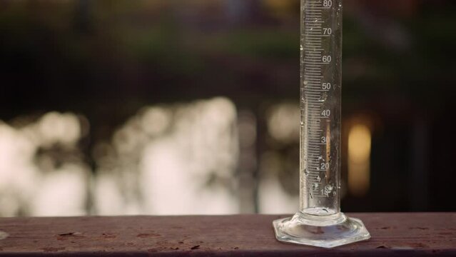 Environmentalistinjects sample water into a measuring cylinder then to examine water quality which presents environmental or pollution and contamination concepts.