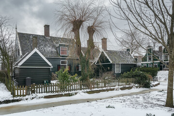 Winter landscape with frozen canal and traditional wooden house in Zaanse Schans, Netherlands.