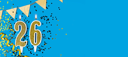 Number 26 gold celebration candle on star and glitter blue background. Copy space.