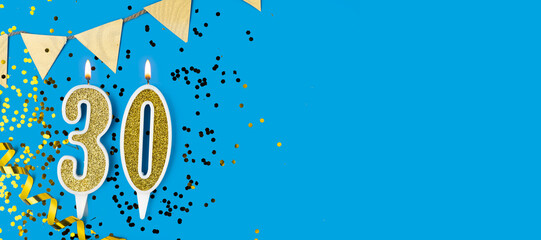 Number 30 gold celebration candle on star and glitter blue background. Copy space.