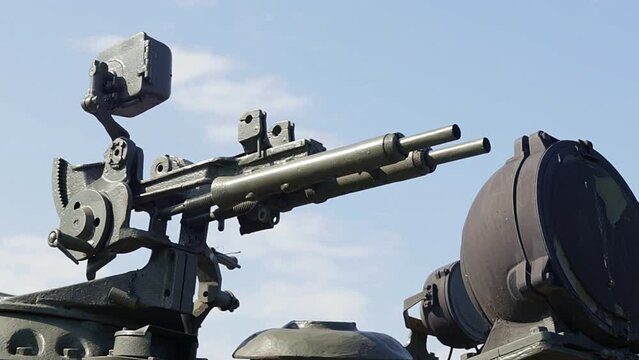 Machine gun on the turret of an armored personnel carrier. Heavy weapons of war, blue sky background. Army equipment for combat and defense. A machine gun mounted on a tank.