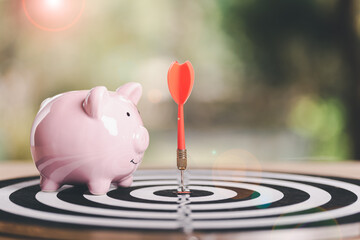 dart arrow hitting in target center of dartboard,and piggy bank, savings goals and growth-oriented...