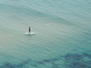 woman slim exercising surf paddle board in turquoise tropical clear waters in Biarritz - obrazy, fototapety, plakaty