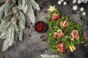 Salad with Serrano jamon, ham, rucola and Parmesan cheese on black background, Christmas food tree...