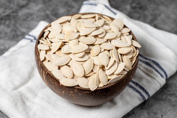 Pumpkin seeds on dark background. Shelled pumpkin seeds in a coconut bowl. close up