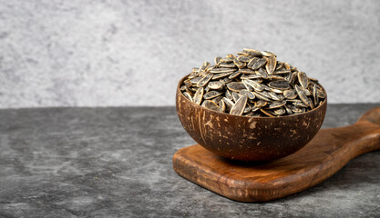 Shelled sunflower seeds on dark background. Salted sunflower seeds in a coconut bowl. Copy space