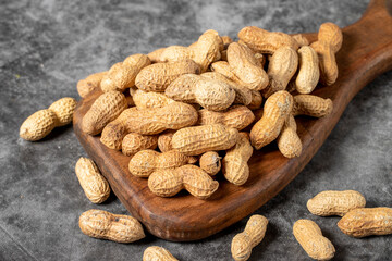 Peanuts in shell on dark background. Peanuts on a wooden serving board. close up