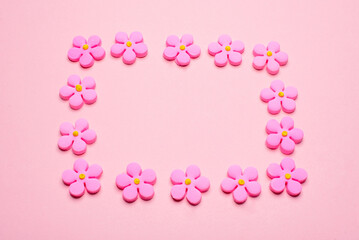 Fototapeta na wymiar Rectangular frame made with sugar flowers on pink background. Love concept