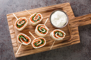 Tasty rolls with salmon, cheese and vegetables for a brunch closeup on the board on the table. Horizontal top view from above - obrazy, fototapety, plakaty