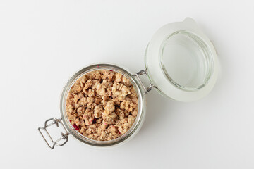Granola in jar on light background.