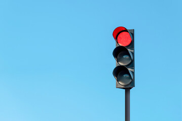 Modern traffic light with red light in front of cloudless sunny blue sky - Powered by Adobe