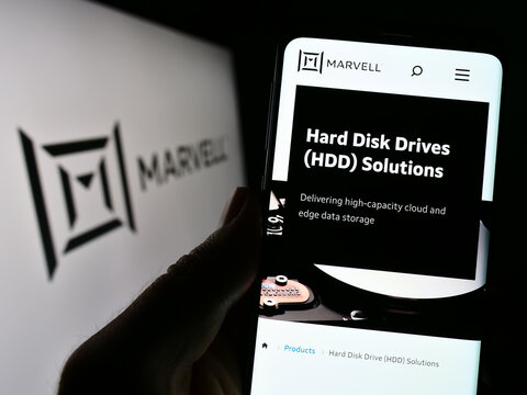 Stuttgart, Germany - 12-30-2022: Person holding cellphone with webpage of US semicondurctor company Marvell Technology Inc. on screen with logo. Focus on center of phone display.