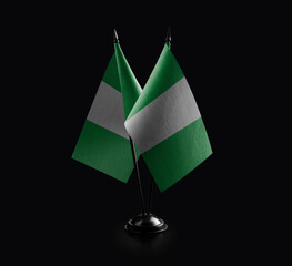 Small national flags of the Nigeria on a black background