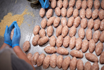 Semi-finished and  raw meat cutlets  with breadcrumbs on restaurant kitchen. Chef are cooking. Close up with gloved hands. Natural and healthy food.  Products ready for cooking or froze.