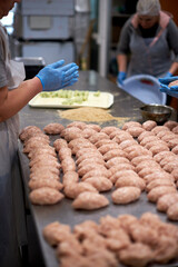 Semi-finished and  raw meat cutlets  with breadcrumbs on restaurant kitchen. Chef are cooking. Close up with gloved hands. Natural and healthy food.  Products ready for cooking or froze.