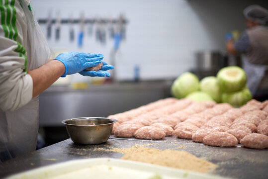 Semi-finished and  raw meat cutlets  with breadcrumbs. Chef are cooking. Close up with gloved hands. Natural and healthy food.  Products ready for cooking or froze.