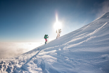two climbers climb the mountain. Two girls climb a snow-covered mountain.