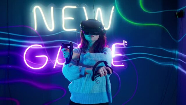 Cyber gamer in VR glasses plays virtual reality game in neon futuristic space. Cyberpunk fashion gaming concept. Man and woman play metaverse virtual digital technology game control with VR goggle.