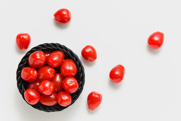 Cherry tomatoes in black basket on white background.