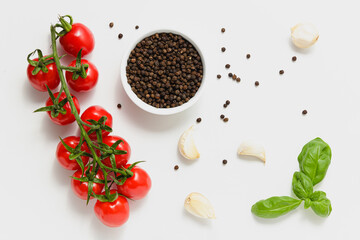 Cherry tomatoes, green basil leaves and pepper on white background.
