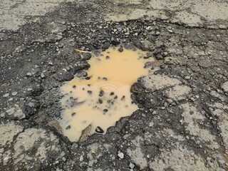 Condition of poor damage asphalt road with pothole fill with rain water seriously in need of repair immediately