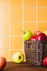 Red and yellow apples in a basket on a wooden table